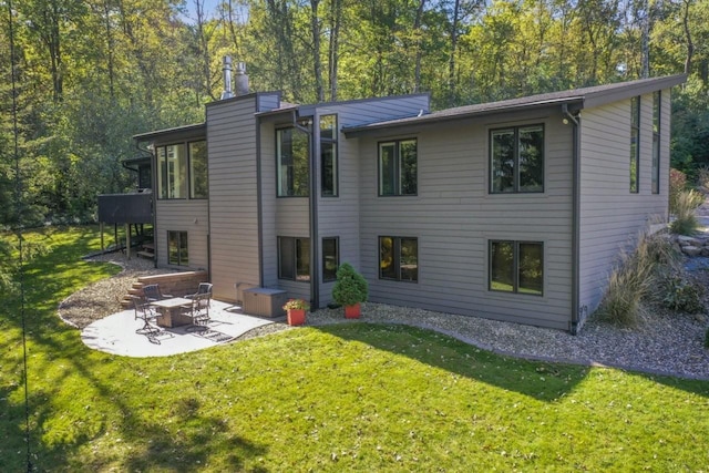 rear view of property with a lawn, a chimney, and a patio