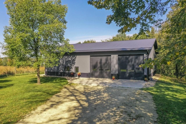 back of property featuring metal roof, a yard, and driveway