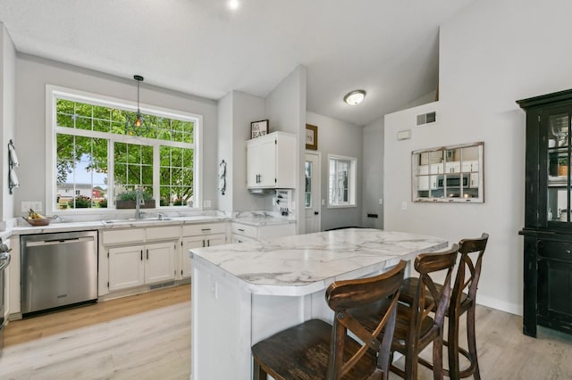 kitchen featuring lofted ceiling, a sink, visible vents, white cabinets, and stainless steel dishwasher