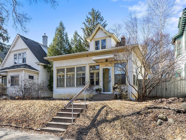 view of front of property featuring stucco siding, fence, and a chimney