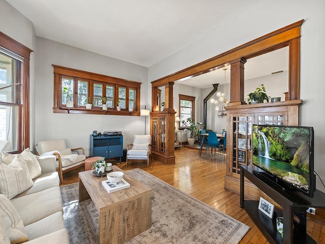 living area with decorative columns, a notable chandelier, and hardwood / wood-style flooring