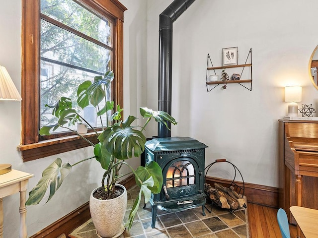 interior details with baseboards, wood finished floors, and a wood stove