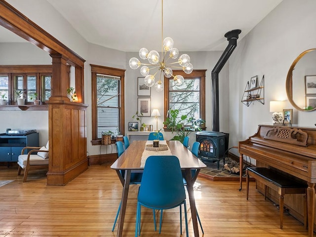 dining room with baseboards, light wood-style flooring, and a wood stove