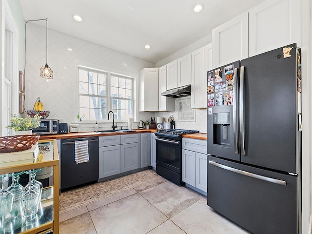 kitchen featuring dishwashing machine, gas stove, butcher block countertops, under cabinet range hood, and fridge with ice dispenser