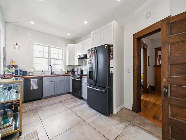 kitchen featuring backsplash, black appliances, under cabinet range hood, white cabinetry, and a sink