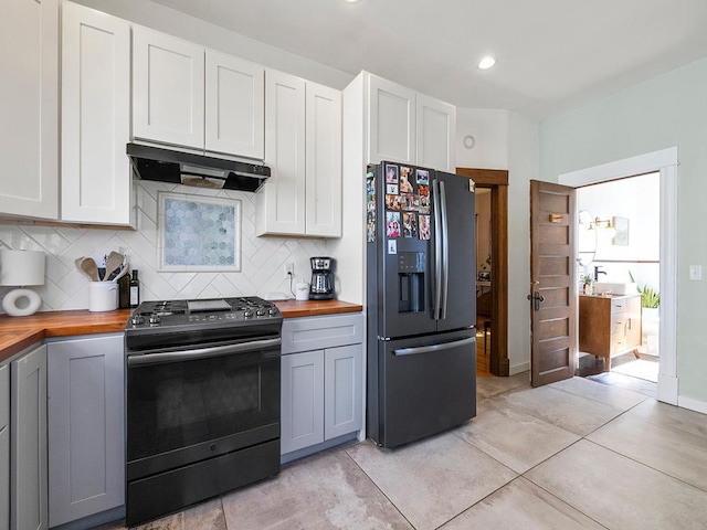 kitchen featuring under cabinet range hood, butcher block countertops, refrigerator with ice dispenser, decorative backsplash, and black range with gas cooktop