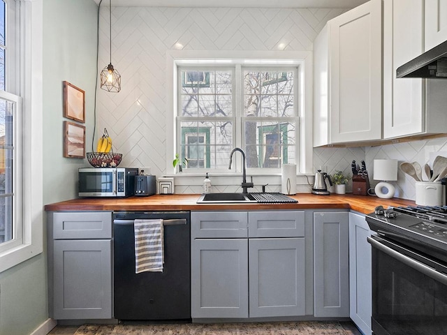 kitchen featuring range hood, gray cabinetry, stainless steel appliances, and wood counters