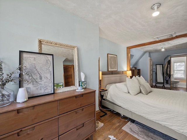 bedroom featuring attic access, visible vents, dark wood-style flooring, and a textured ceiling