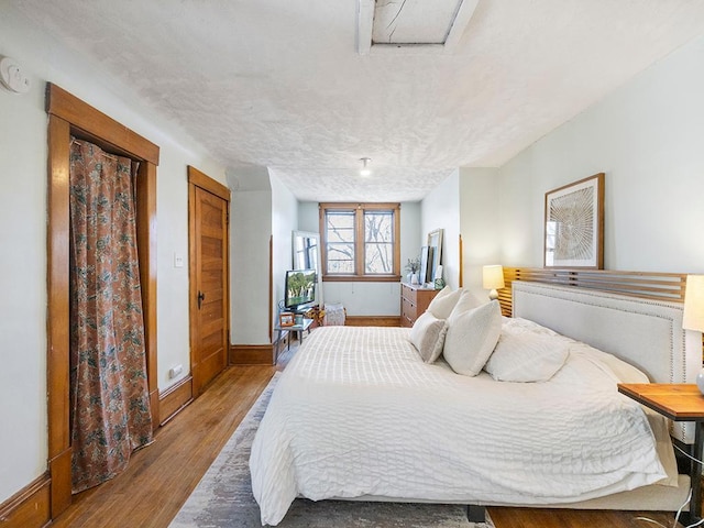 bedroom featuring baseboards, a textured ceiling, and wood finished floors