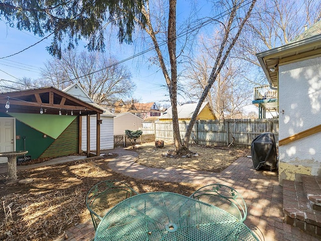 view of yard featuring an outdoor structure, outdoor dining area, fence, and a patio area