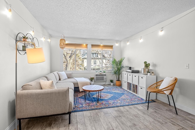 living area with a textured ceiling, an AC wall unit, wood finished floors, and track lighting