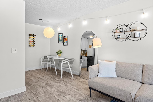 living area with track lighting, a textured ceiling, baseboards, and wood finished floors