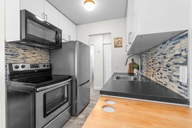 kitchen with stainless steel electric stove, a sink, black microwave, a textured ceiling, and white cabinetry