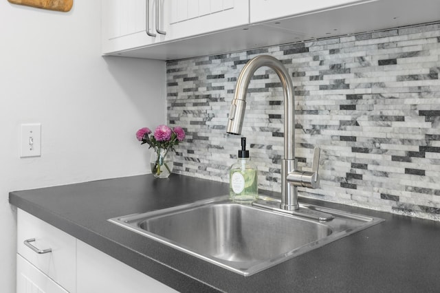 room details with dark countertops, white cabinets, tasteful backsplash, and a sink