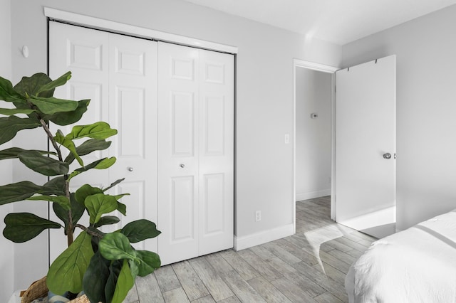 bedroom featuring a closet, baseboards, and light wood finished floors