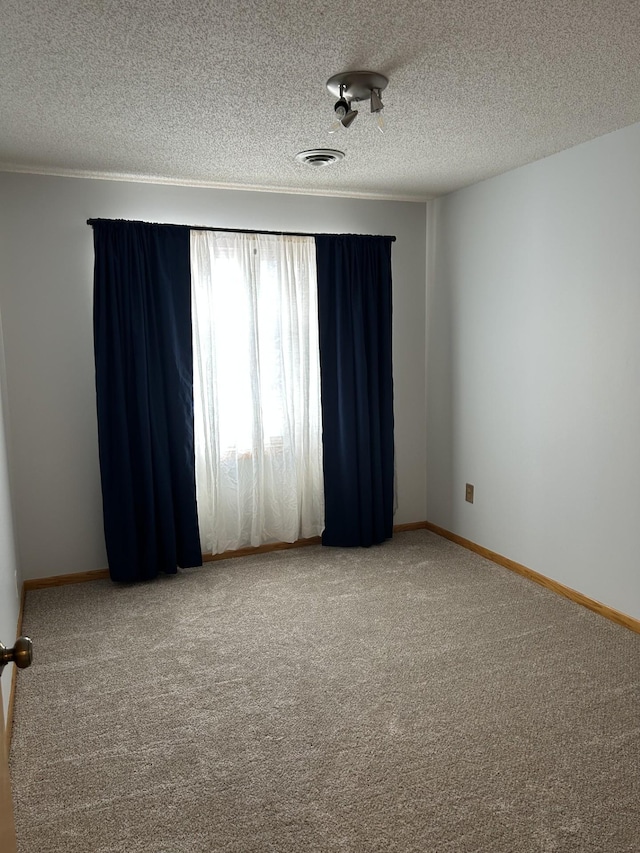 unfurnished room with carpet, a textured ceiling, and baseboards