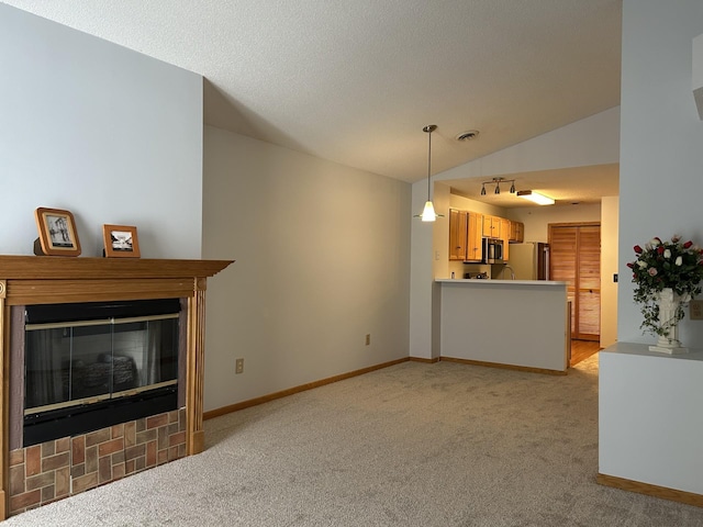 unfurnished living room featuring light colored carpet, visible vents, a glass covered fireplace, vaulted ceiling, and baseboards