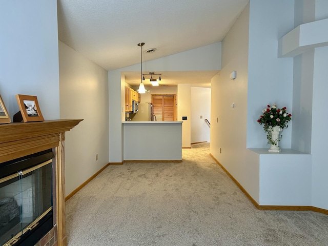 unfurnished living room featuring a glass covered fireplace, light carpet, vaulted ceiling, and visible vents