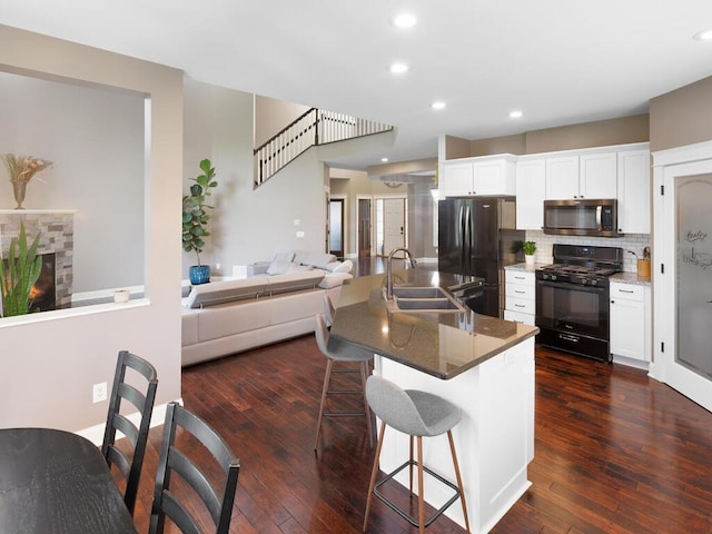 1757 Sandbar Cir, Waconia, MN 55387 - kitchen with black appliances, a sink, a breakfast bar area, white cabinets, and open floor plan