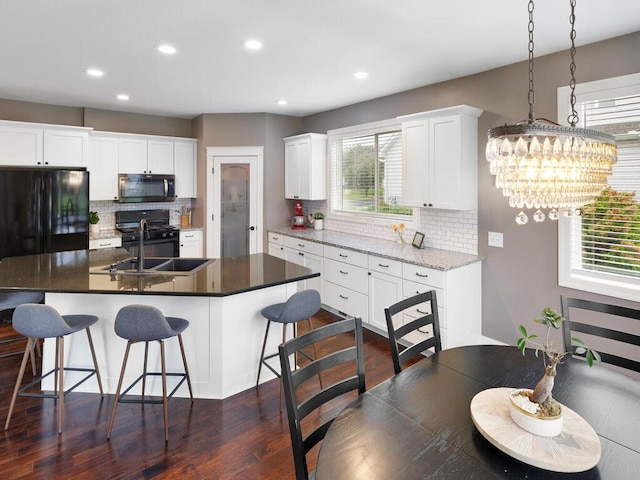 1757 Sandbar Cir, Waconia, MN 55387 - kitchen featuring black appliances, a sink, decorative backsplash, a breakfast bar area, and dark wood-type flooring