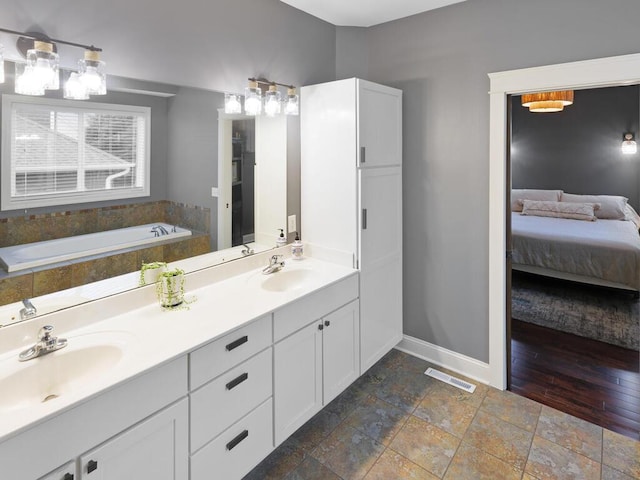 1757 Sandbar Cir, Waconia, MN 55387 - ensuite bathroom featuring baseboards, a sink, stone tile floors, and a bath