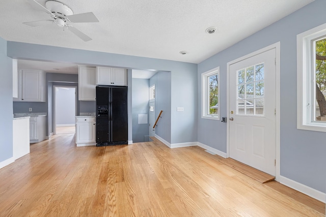 kitchen featuring light wood-style floors, a wealth of natural light, and black fridge