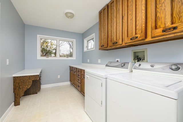 clothes washing area featuring light floors, washer and clothes dryer, cabinet space, and baseboards