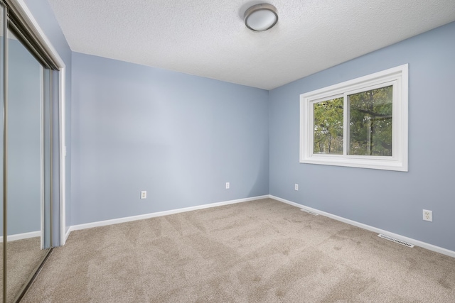 unfurnished bedroom with carpet, a closet, a textured ceiling, and baseboards