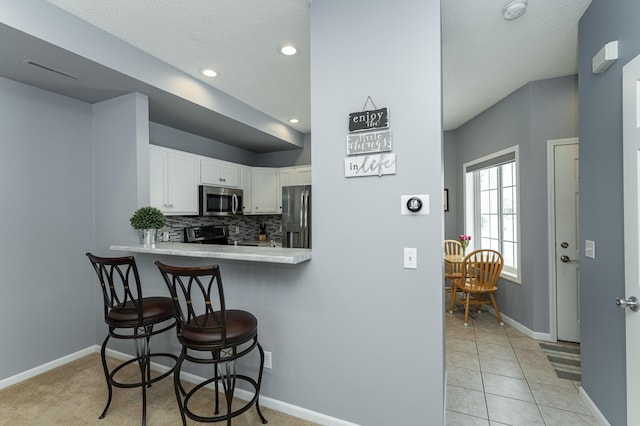 1868 Tiffany Cove Ln SW, Rochester, MN 55902 - kitchen featuring appliances with stainless steel finishes, a kitchen breakfast bar, white cabinetry, baseboards, and a textured ceiling
