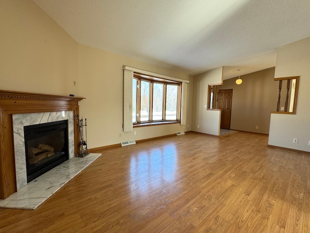 unfurnished living room featuring wood finished floors, visible vents, baseboards, and a premium fireplace