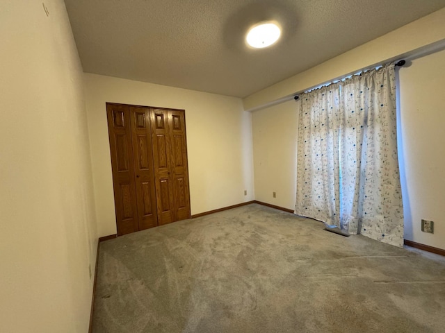 unfurnished bedroom with a closet, carpet flooring, a textured ceiling, and baseboards