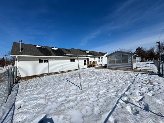 snow covered rear of property featuring fence and a wooden deck