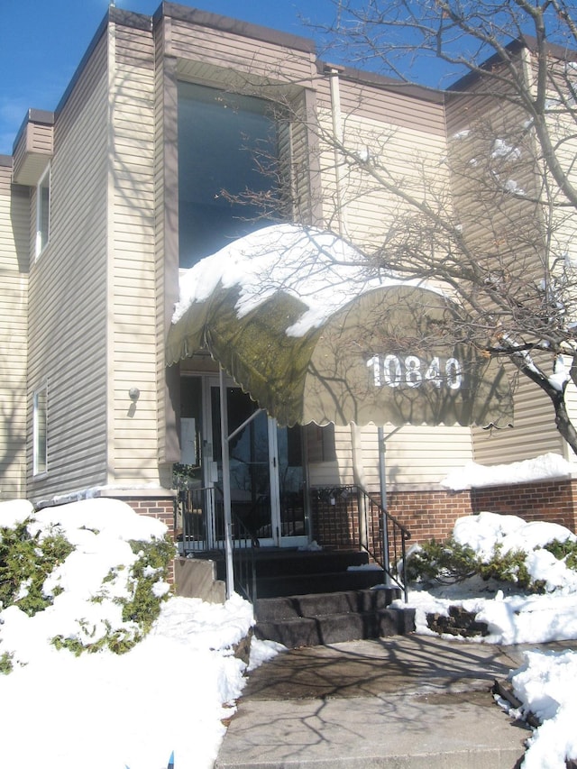 snow covered property with french doors and brick siding