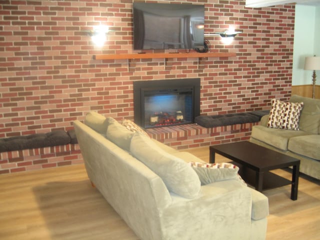 living room with a brick fireplace and wood finished floors