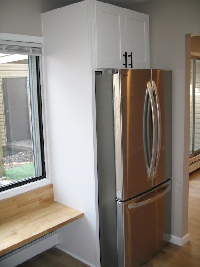 kitchen featuring baseboard heating, freestanding refrigerator, white cabinetry, wood counters, and wood finished floors