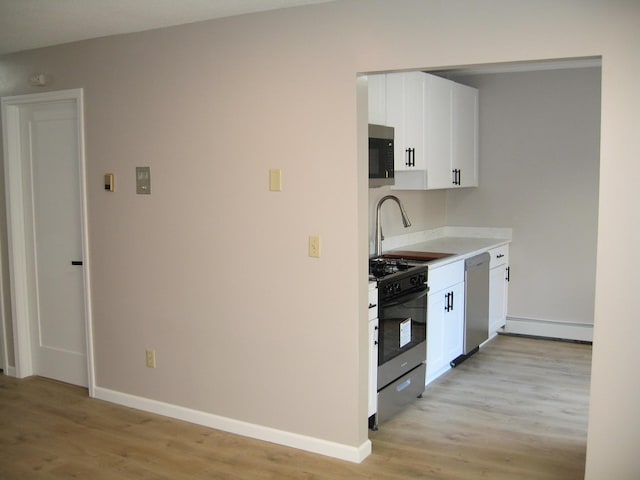 kitchen with range with gas stovetop, light countertops, stainless steel dishwasher, light wood-style floors, and white cabinets