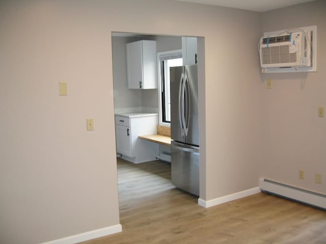 kitchen with light countertops, light wood finished floors, freestanding refrigerator, and baseboards