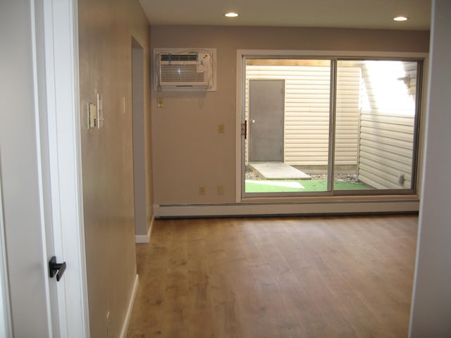 interior space with a baseboard radiator, a wall mounted air conditioner, wood finished floors, and recessed lighting