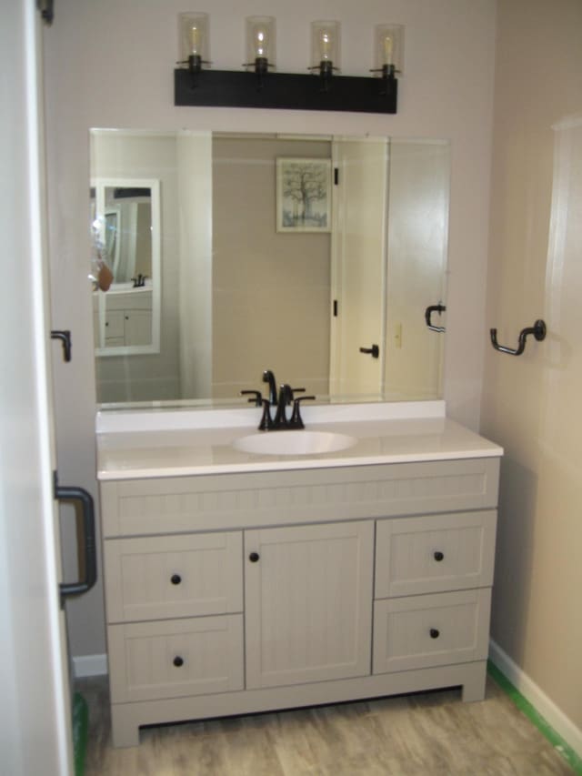 bathroom with wood finished floors, vanity, and baseboards