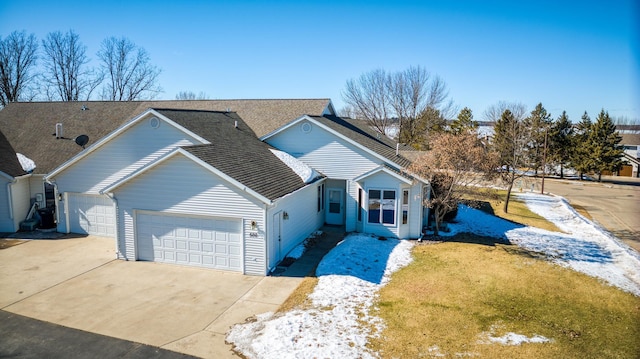 view of front of house featuring an attached garage, a shingled roof, a front lawn, and concrete driveway