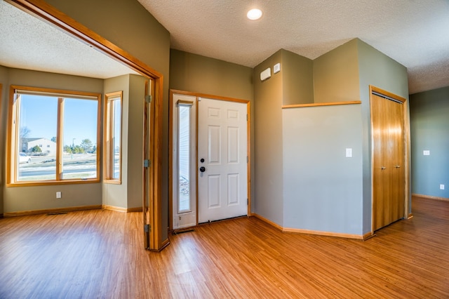 entrance foyer featuring light wood-style floors, baseboards, and a textured ceiling