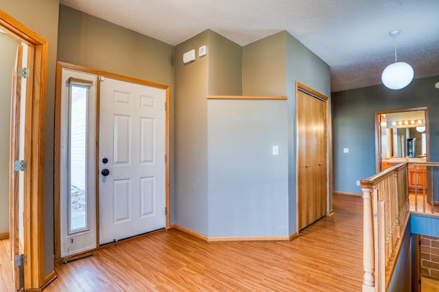 entryway with light wood-type flooring, baseboards, visible vents, and a textured ceiling