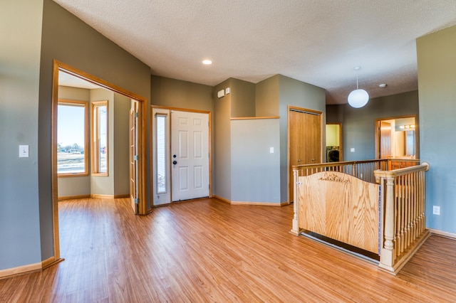 kitchen featuring washer / dryer, light wood-style flooring, baseboards, and a textured ceiling