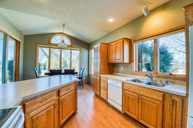 kitchen featuring white dishwasher, a sink, vaulted ceiling, light countertops, and range