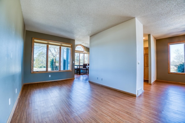 empty room featuring light wood finished floors, visible vents, and baseboards