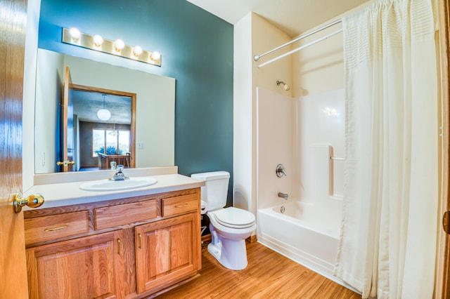 bathroom with toilet, shower / bath combo with shower curtain, wood finished floors, and vanity