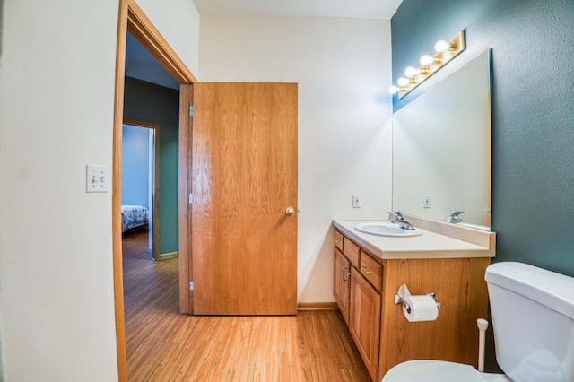 bathroom with baseboards, vanity, toilet, and wood finished floors