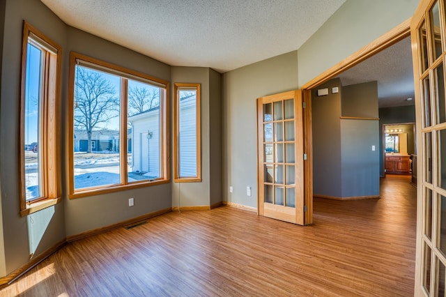 spare room featuring french doors, baseboards, and wood finished floors