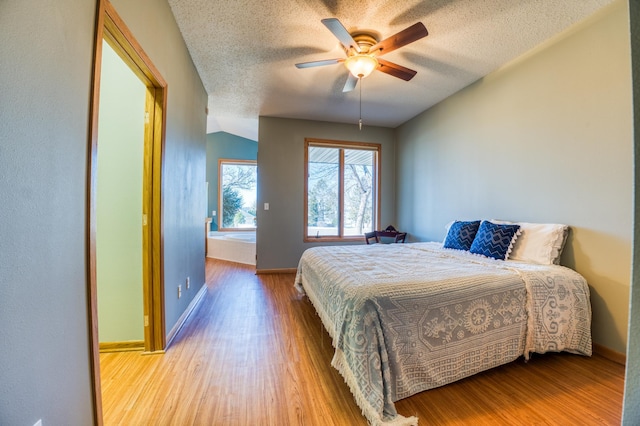 bedroom with ceiling fan, a textured ceiling, baseboards, and wood finished floors