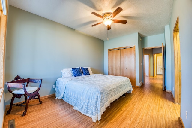 bedroom featuring baseboards, visible vents, a textured ceiling, light wood-type flooring, and a closet